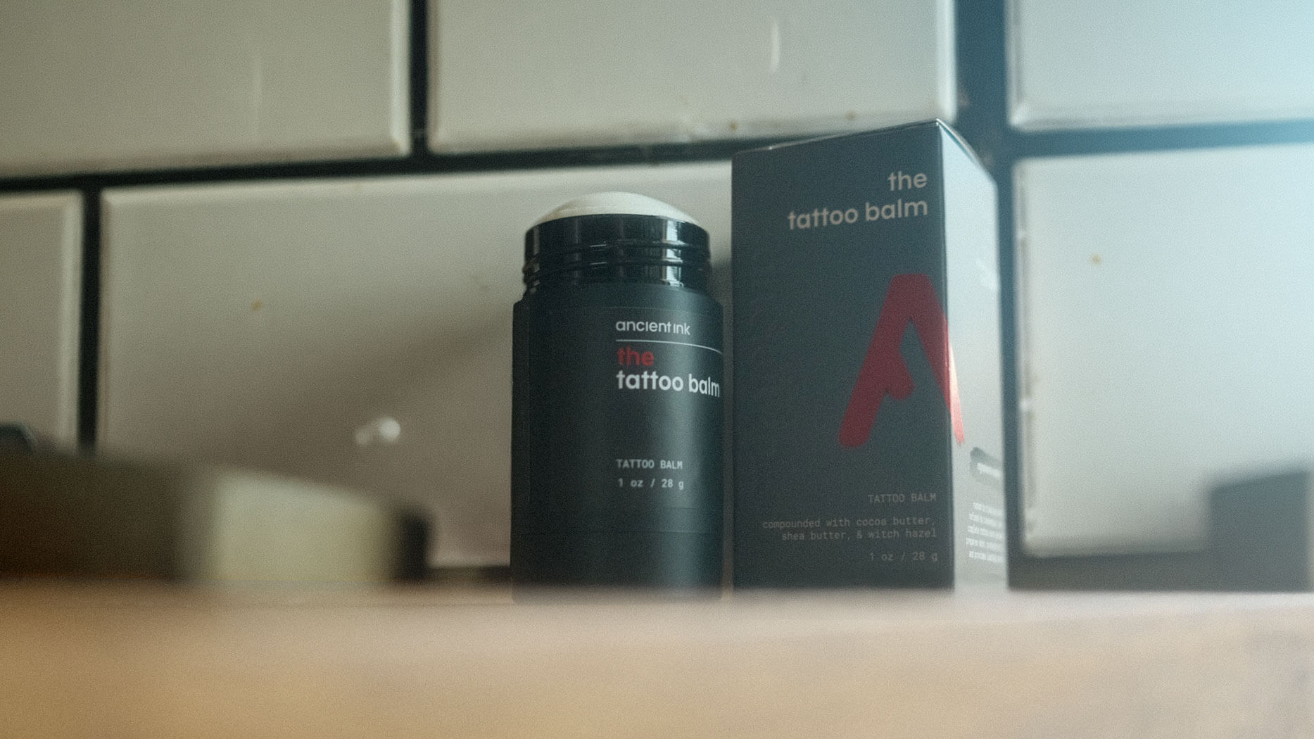 tattoo balm product image with a wood foreground and subway tile background