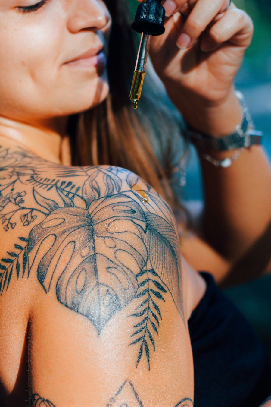 Oil applied by dropper to a healed botanical shoulder tattoo