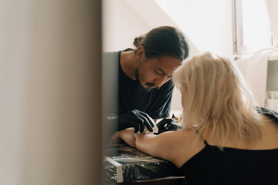 Tattoo artist working on a client's arm in a studio